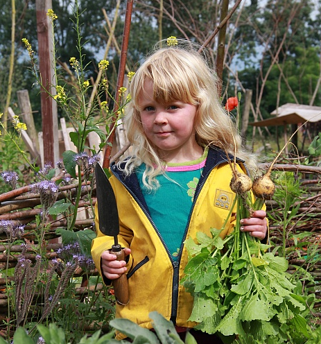 Kind met schep en knol in tuin